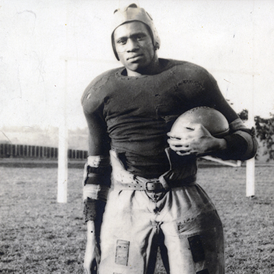 Paul Robeson standing with football in full uniform